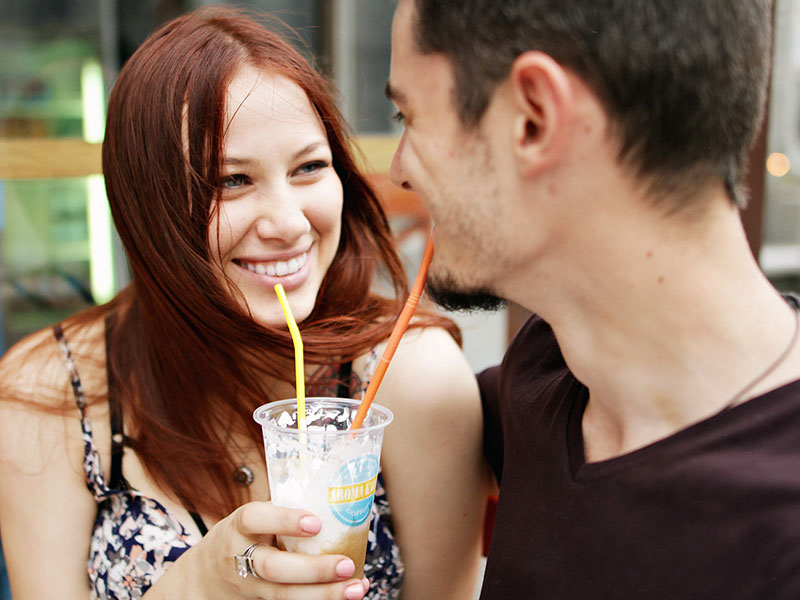 A man wondering what women want in a man, sharing a drink with his girlfriend as she smiles at him.