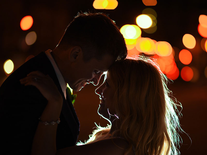 A woman who believes in love at first sight, looking into her boyfriends eyes before they kiss outside at night.