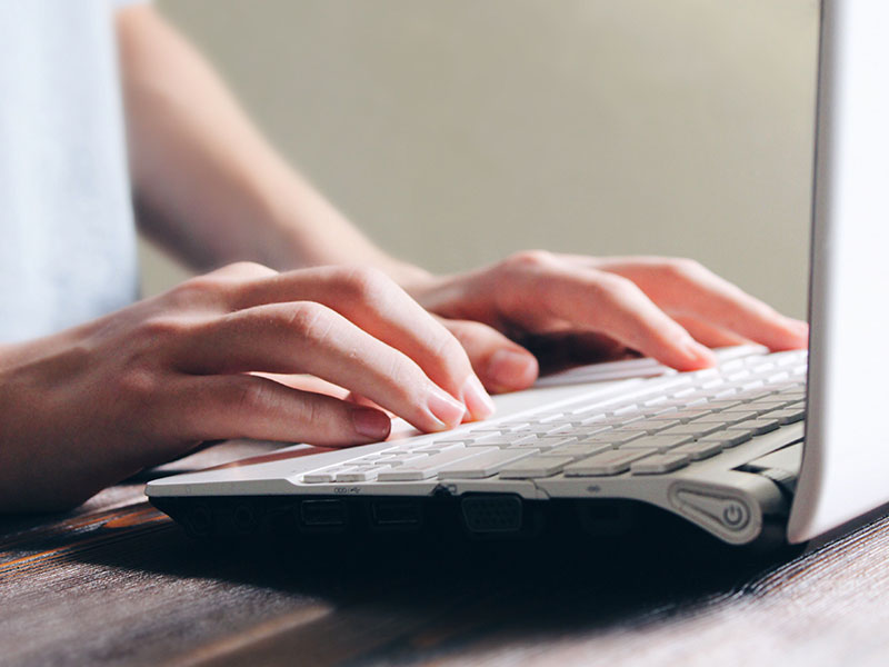 A woman typing on her computer who was a victim of online harassment.