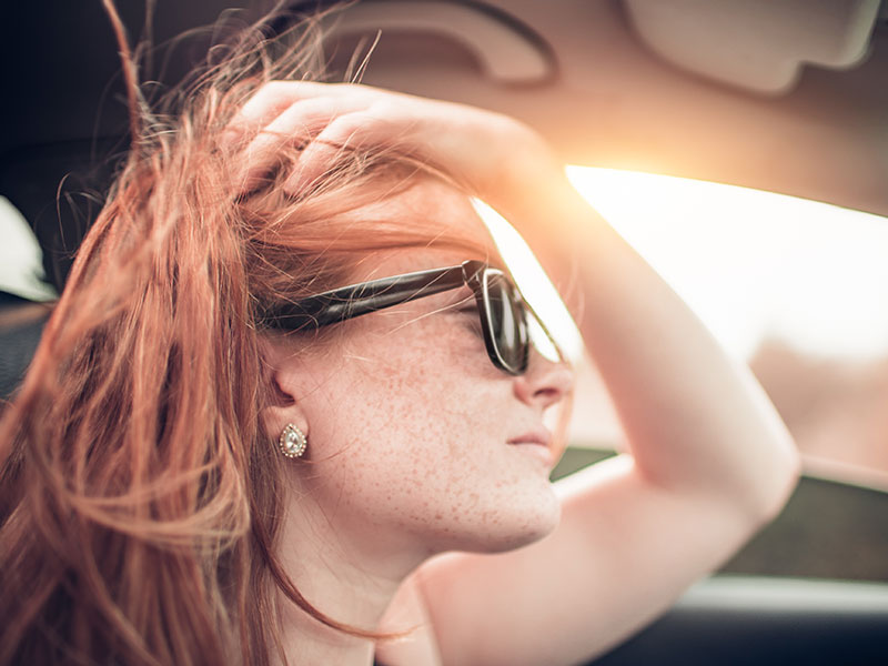A woman who knows it's time to move on, driving in her car at sunset and thinking about her relationship.