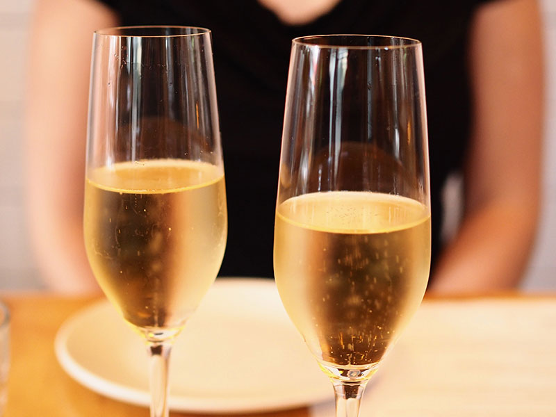 A woman sitting in front of two champagne glasses who took this first date advice to relax and keep it to one drink.
