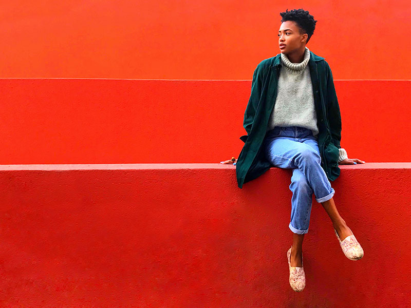 A woman who was thinking of giving up on love, sitting in front of a red wall thinking about how she feels.