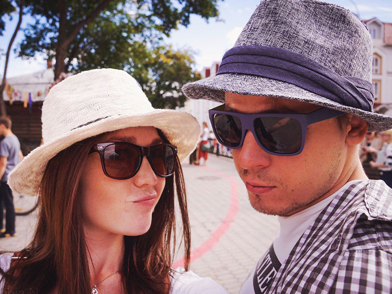 A girl with her guy best friend, making a funny face while wearing similar hats and sunglasses.