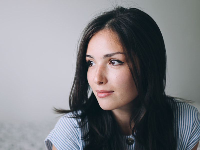 A woman who's having a hard time letting go of a relationship looking off to the distance while thinking.