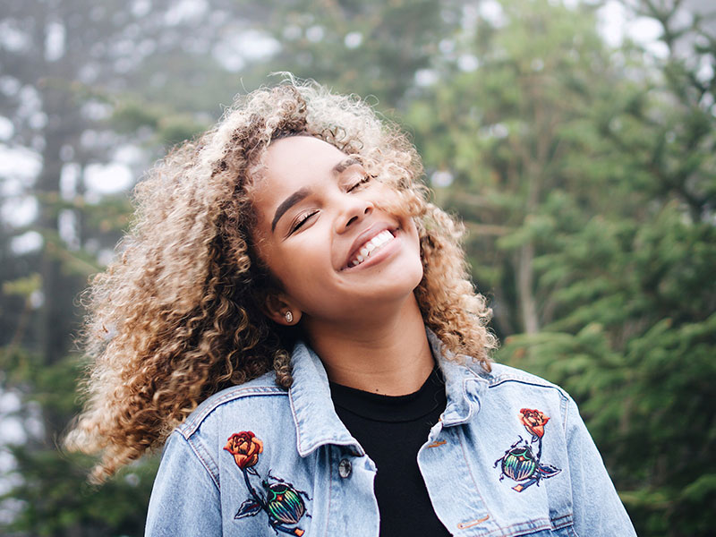 A woman who learned to love yourself first, smiling and laughing at the sky.