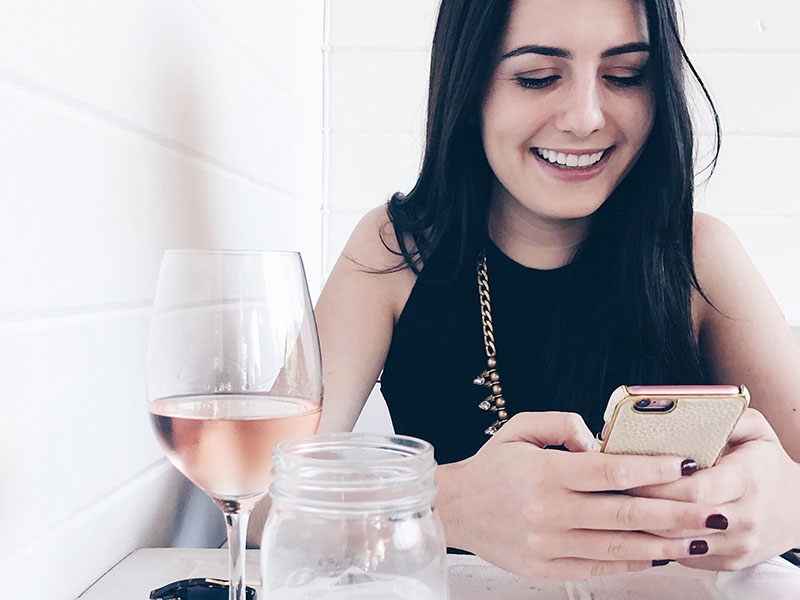 A woman laughing at her phone at one of these sweet pick up lines.