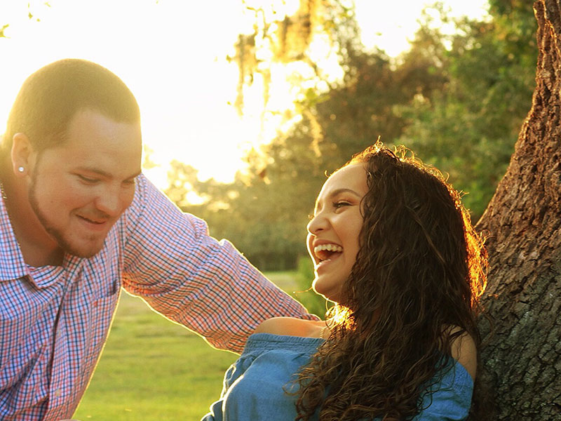 A guy showing signs he's fighting his feelings for you, leaning against a tree talking to the girl he likes trying to keep his cool.
