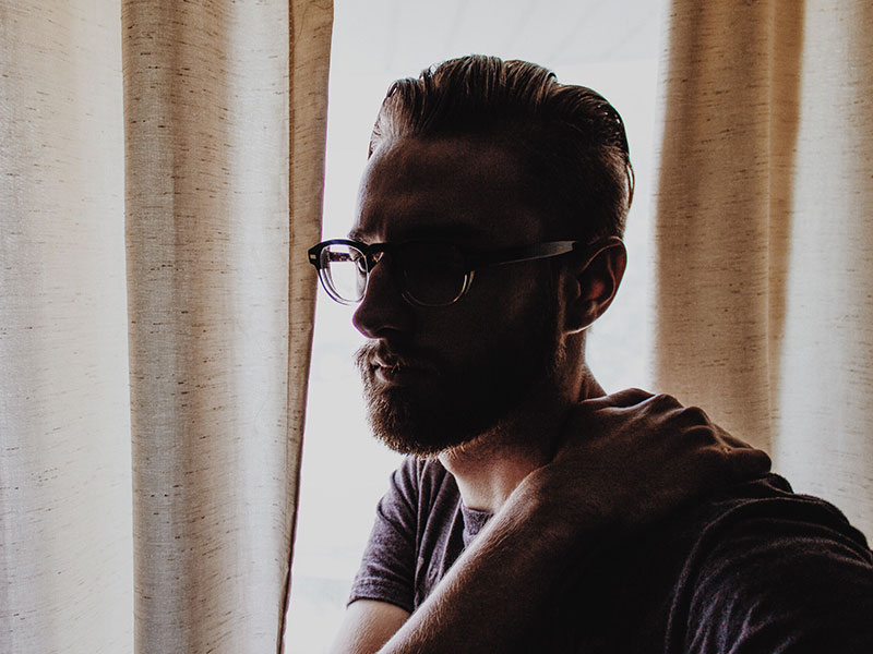 A man who's seen the signs that it's time to break up thinking and looking stressed out a window.