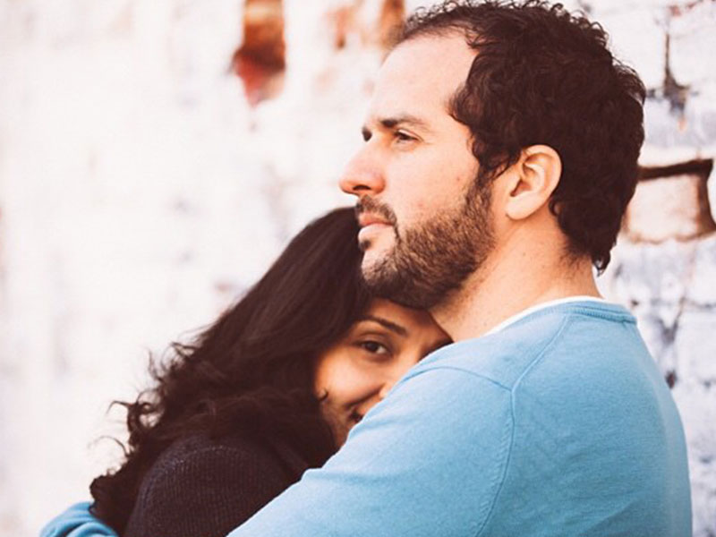 A woman who is wondering what to do when he says he loves you, hugging her boyfriend and smiling.