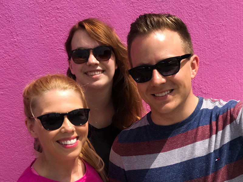 Three people thinking about trying an open relationship smiling as they take a selfie together.