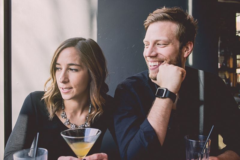 Couple dating at 40, enjoying cocktail and looking out the window together