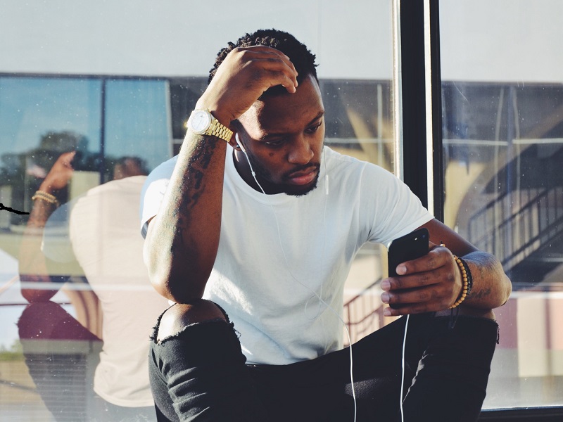 Man looking stressed looking at his phone and working out how to break up with a girl