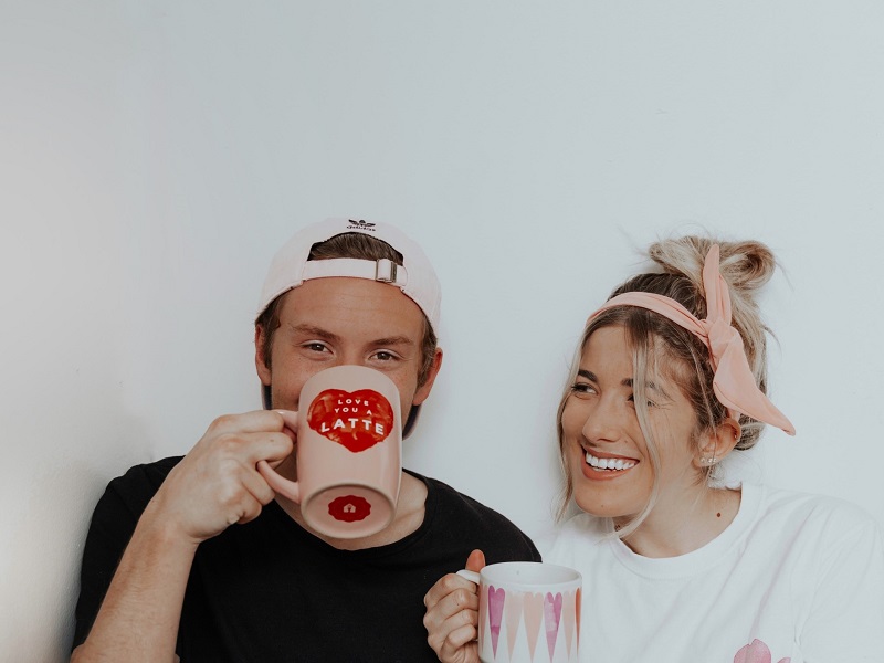 Cute couple laughing and drinking coffee while enjoying unconditional love