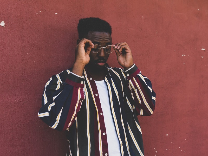 Attractive young man standing in front of red wall and wearing a cool first date outfit for men