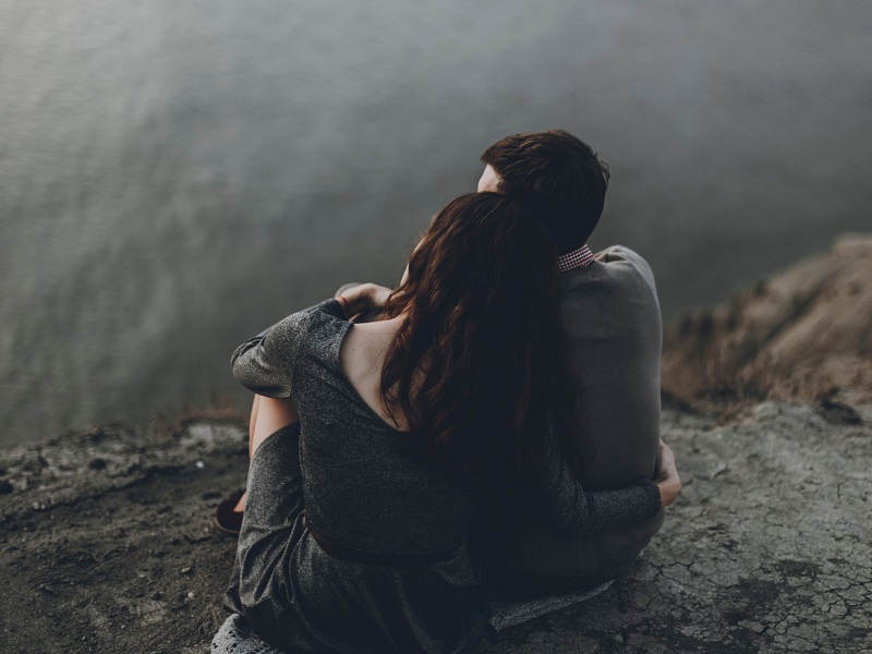 couple sitting on cliff edge discussing pursuer distancer relationship dynamic