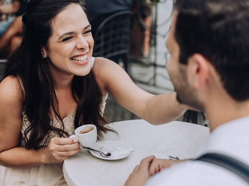 couple drinking coffee and laughing showing the signs she wants a serious relationship with you
