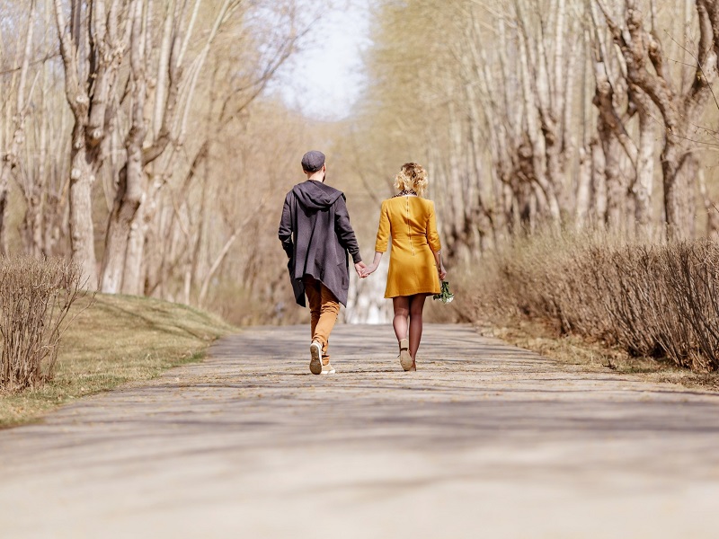 couple holding hands and walking in the park with the lady an example of dating a younger man in your 40s