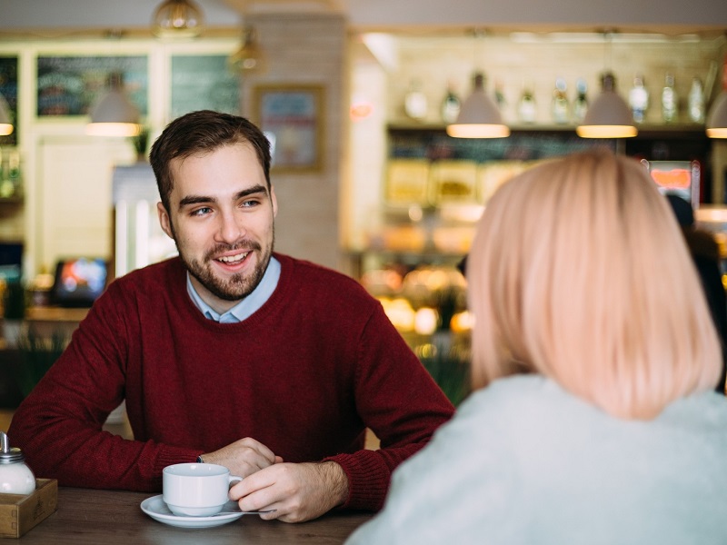 attractive man looking at a woman and flirting in conversation at a coffee shop