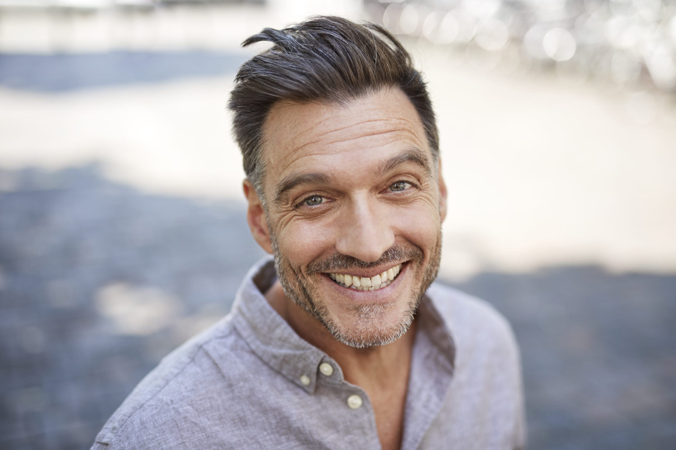 older, attractive single man wearing a grey shirt and smiling
