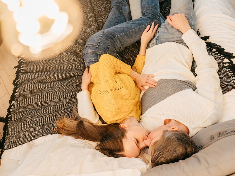 couple lying on bed kissing about to make love