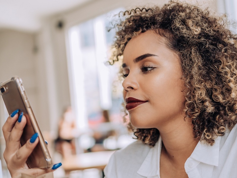 smiling woman using her mbile phone to sending cute paragraphs to her crush