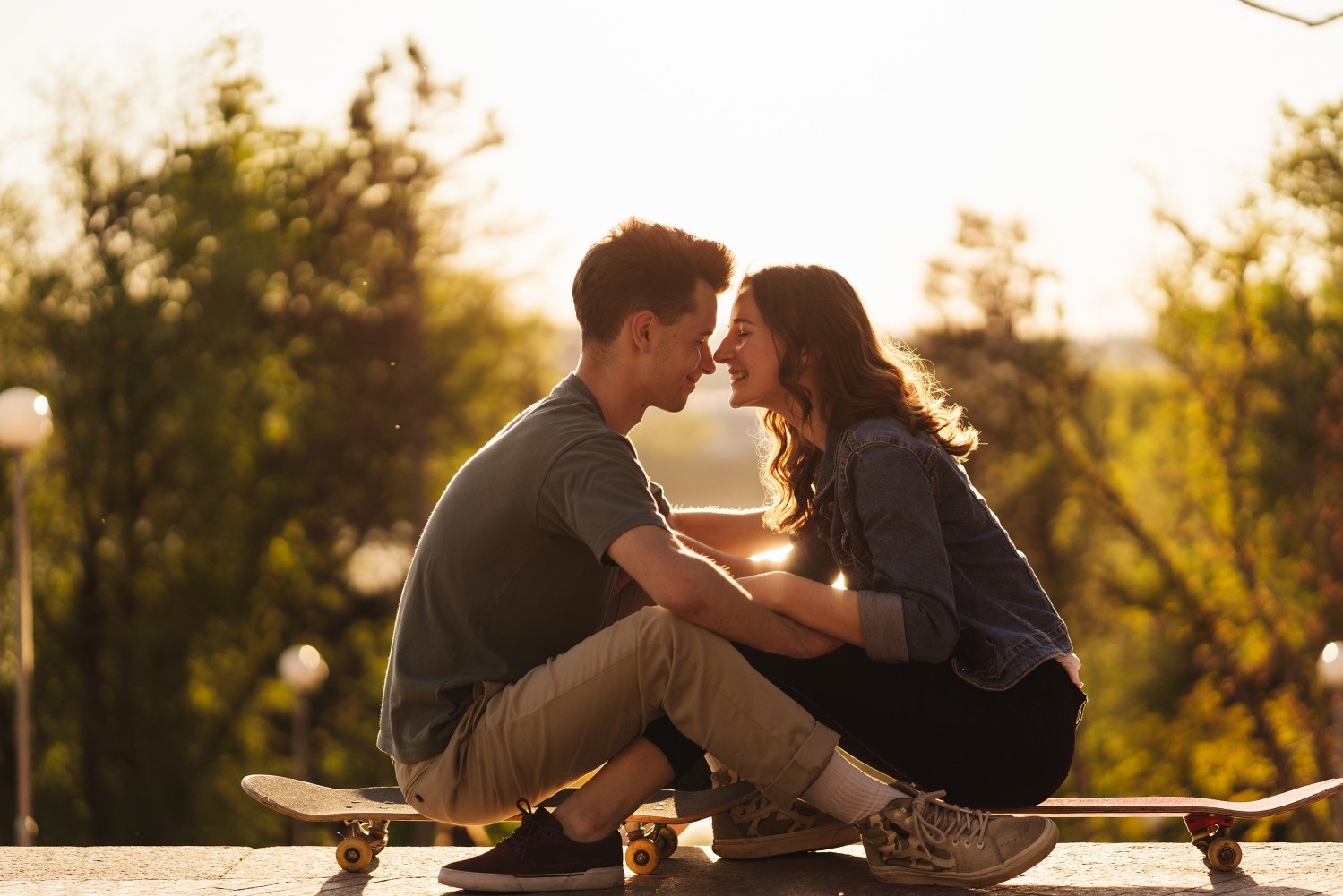 happy couple sitting on skateboards in the sunshine