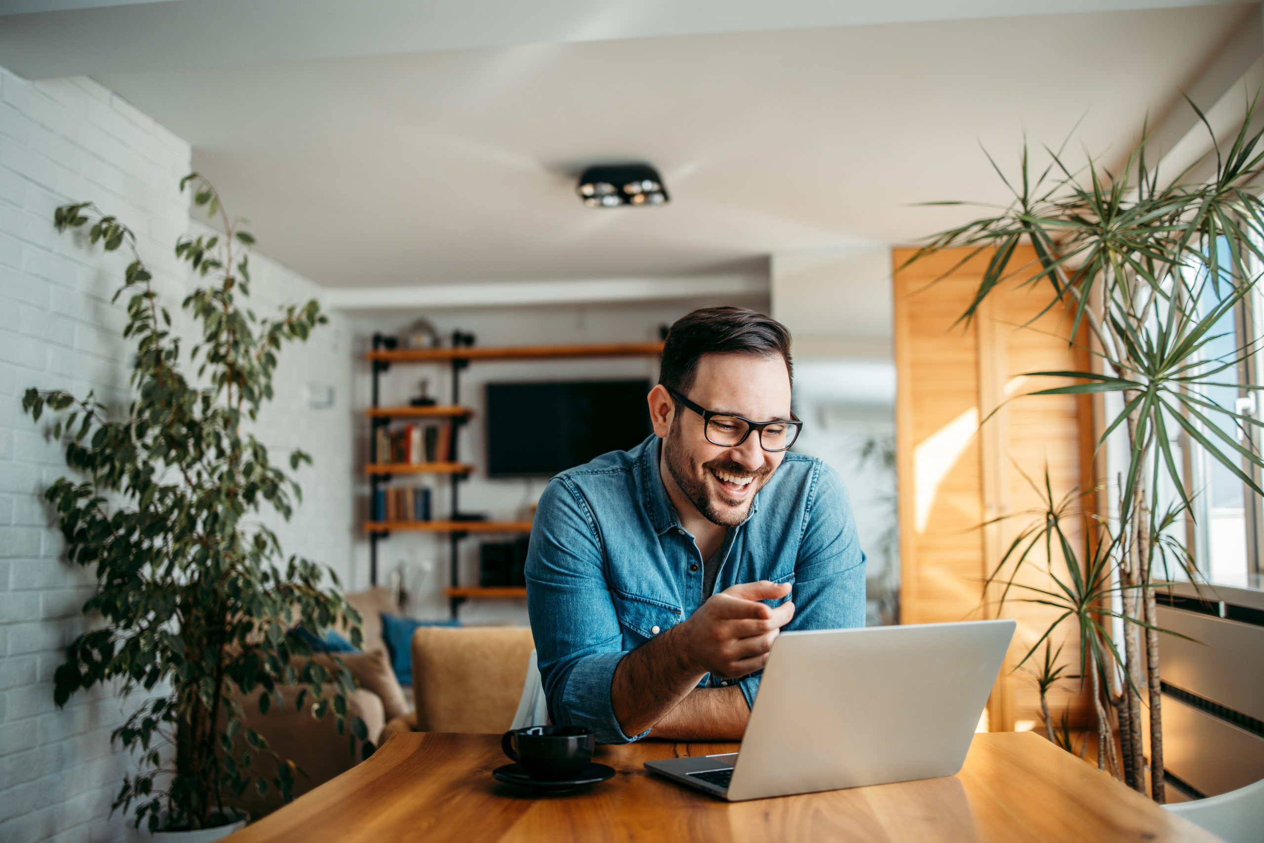 Man sitting at a table using laptop and smiling while virtual dating.