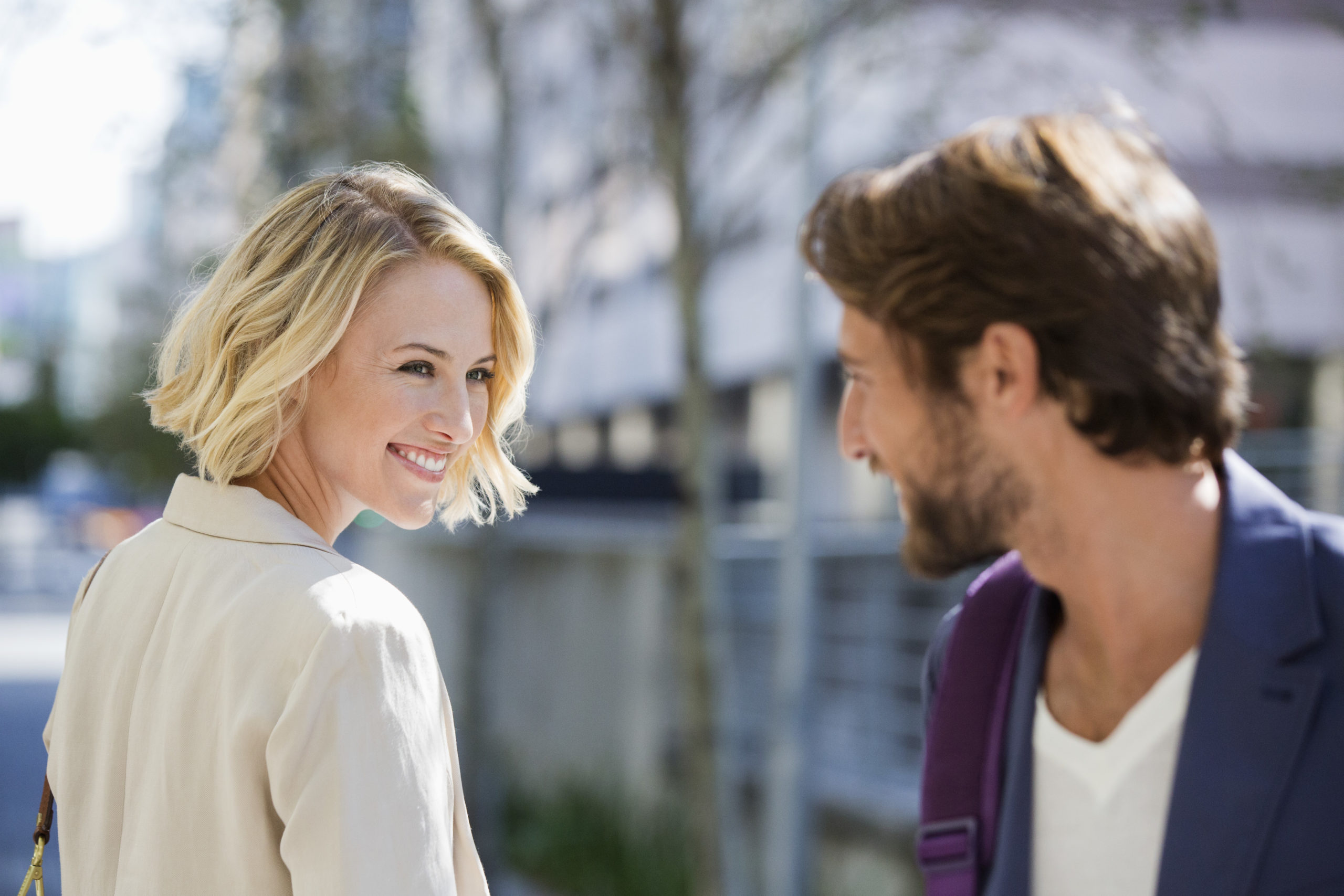 Man and woman smiling at each other in the street as man figures out how to meet women.