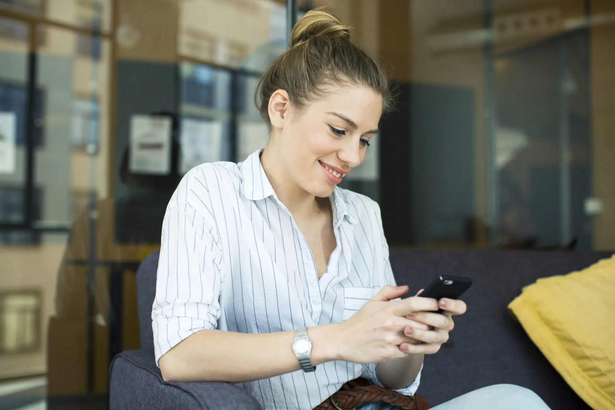 Happy, smiling woman using mobile phone to practice ways of how to flirt over text.