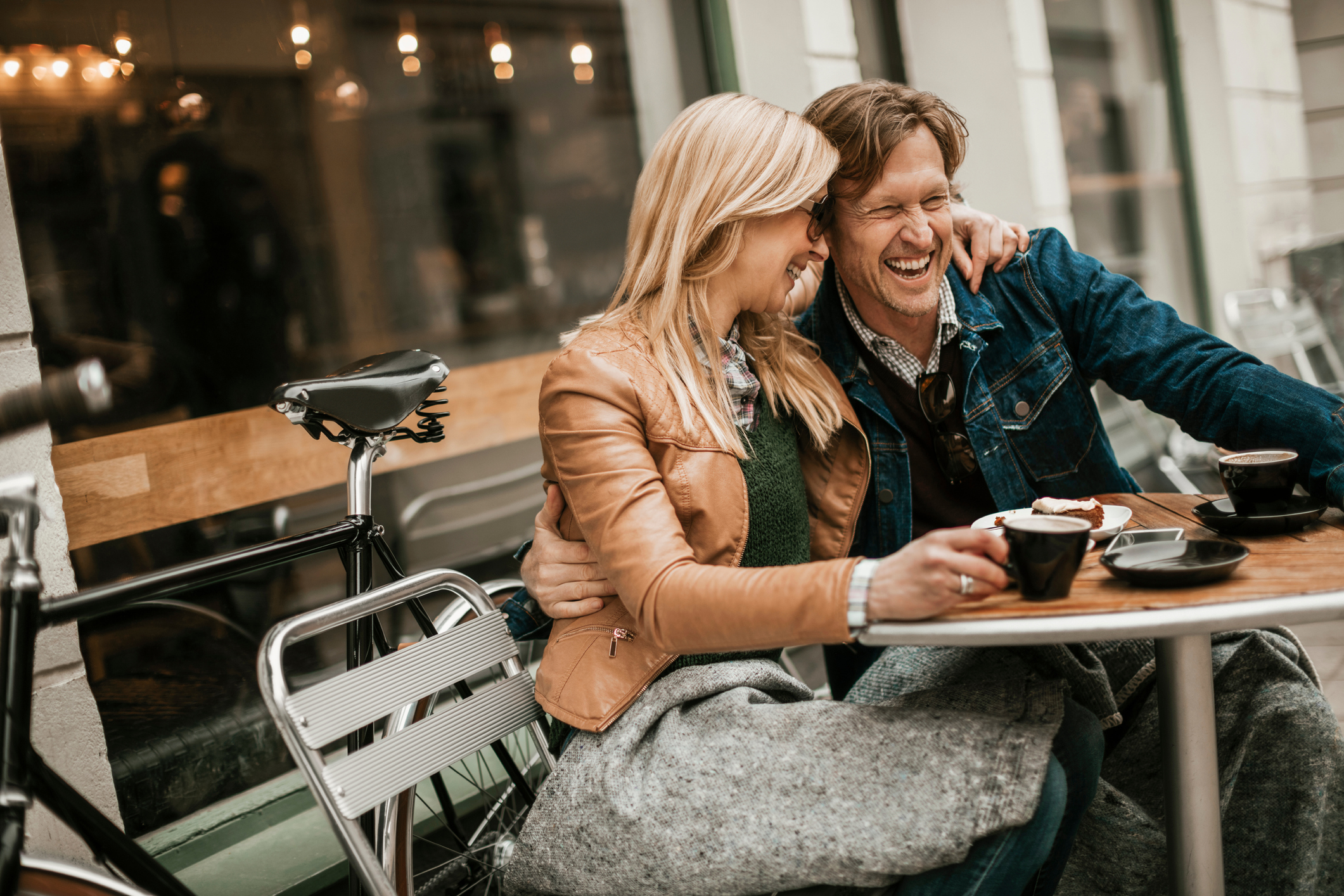 Happy couple sitting in a cafe and laughing together while dating in Buffalo NY.