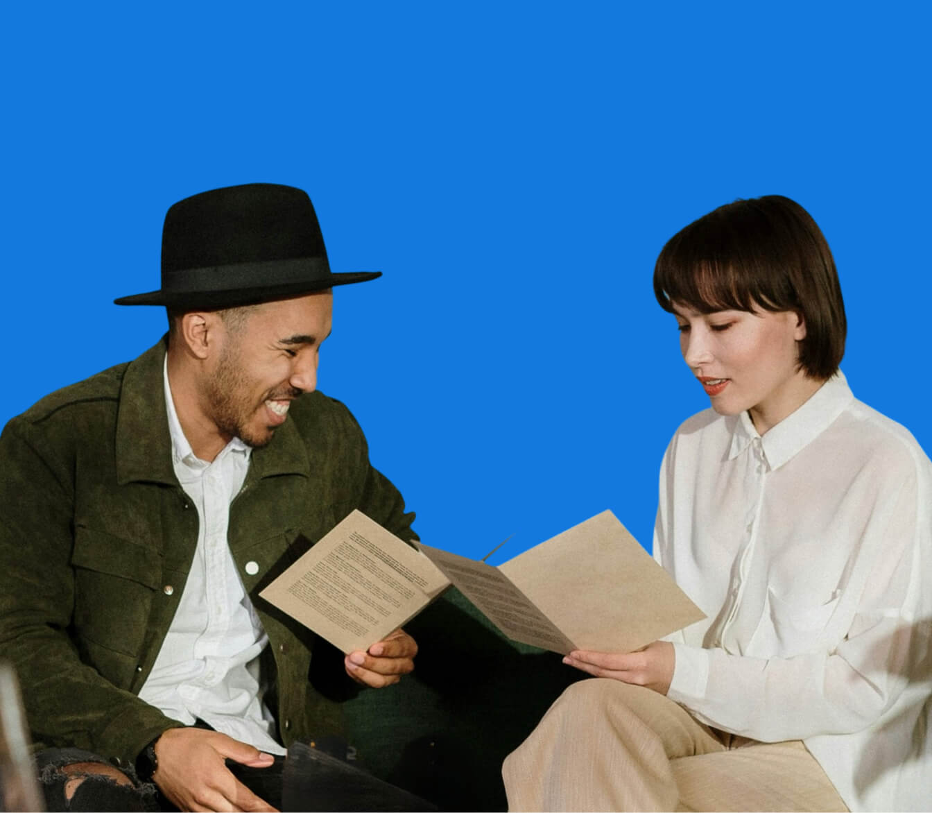 A man and woman sit together, both engrossed in reading a book.