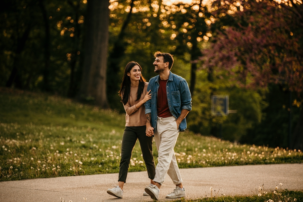 Couple strolling in the park while holding hands.